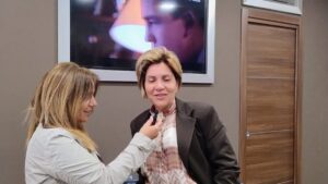 Intervista a una donna durante un evento indoor mentre una giornalista le porge il microfono in un contesto informativo