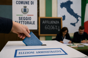 Scheda elettorale inserita nell’urna durante le elezioni amministrative italiane 2026 con dati sull’affluenza in calo e simboli istituzionali sullo sfondo.