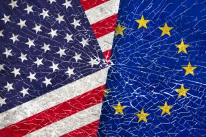 Donald Trump e Friedrich Merz al centro delle tensioni tra Stati Uniti ed Europa con bandiere USA e UE sullo sfondo