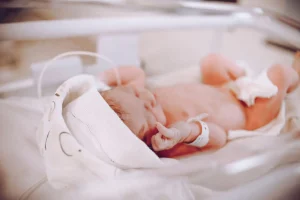 Neonato in culla trasparente.