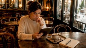 Una donna comodamente seduta in salotto si tiene aggiornata sulle ultime notizie leggendo dal suo tablet.