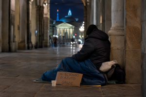 Povertà a Torino con una persona senza dimora sotto i portici