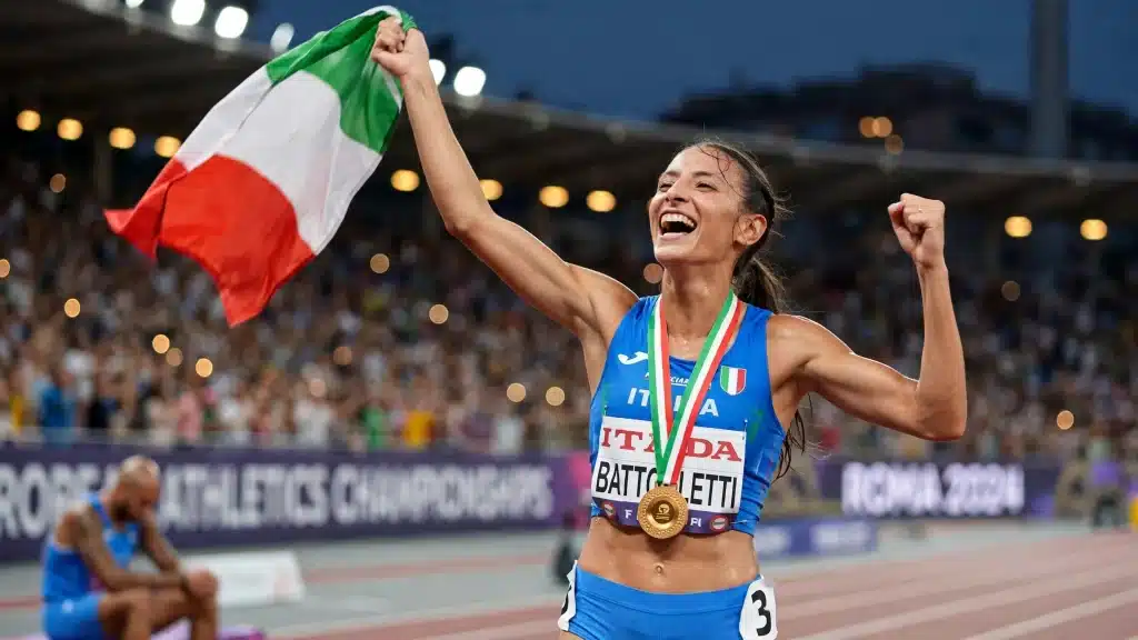 Una atleta con la bandiera italiana che la sventola