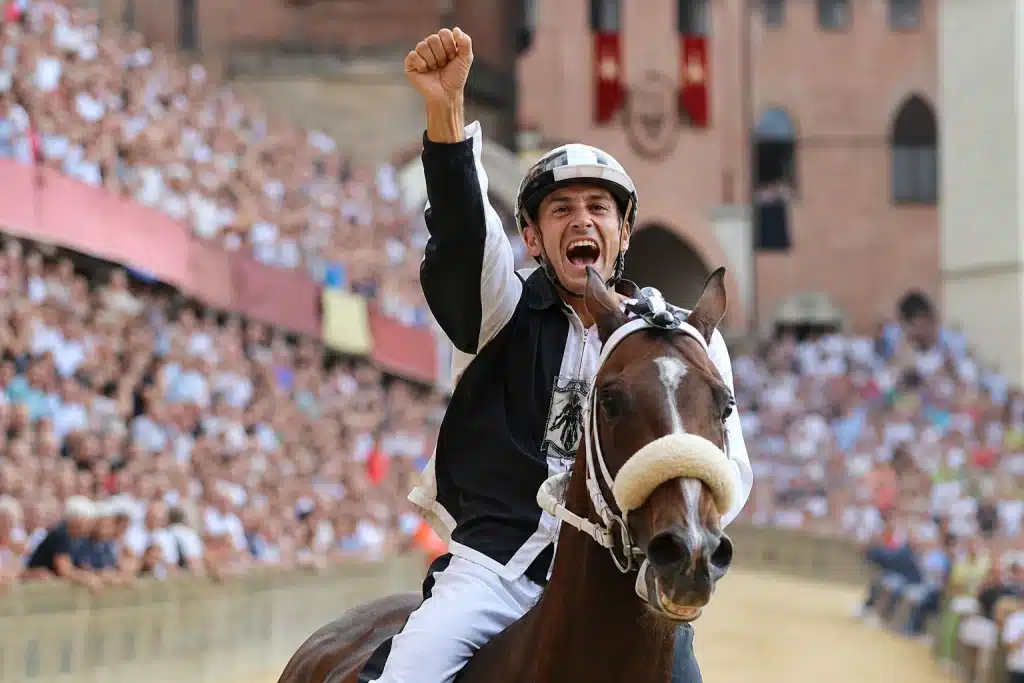 Un fantino esulta dopo il Palio di Siena
