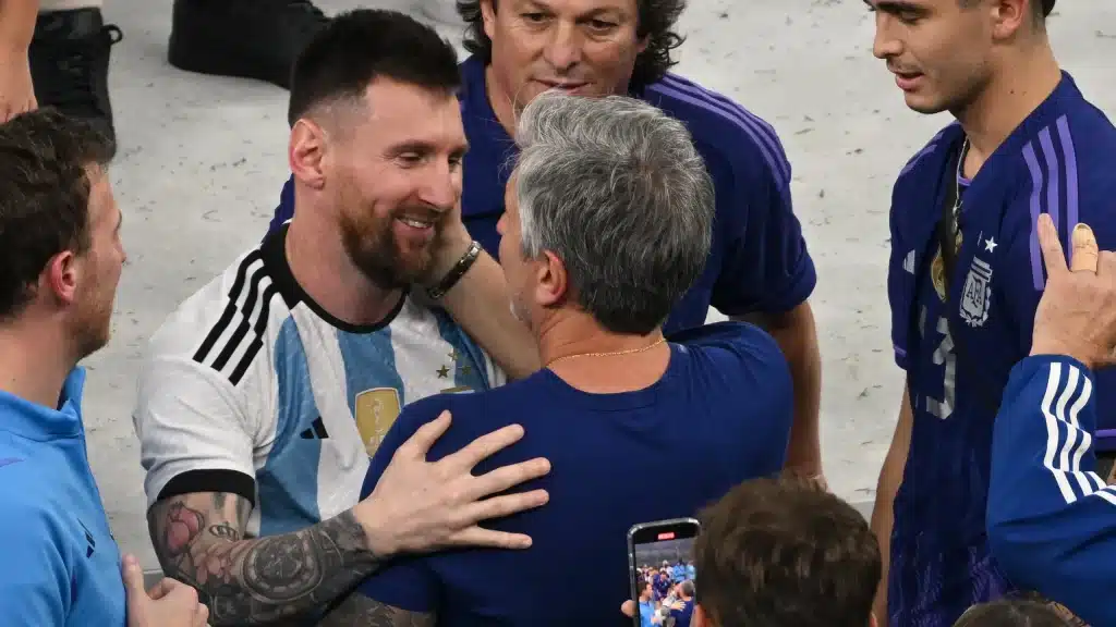 Messi abbraccia un allenatore sorridente.