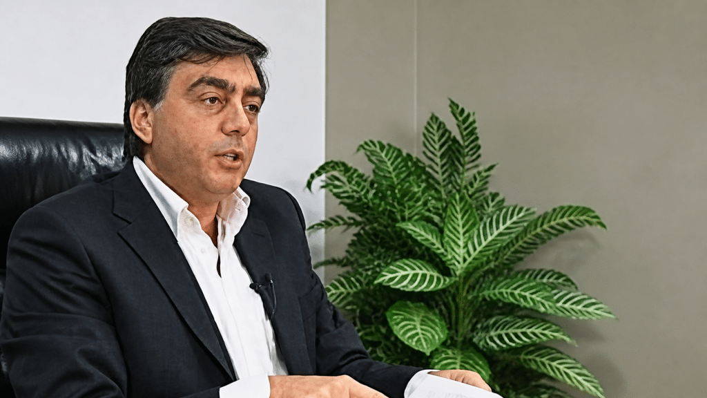 Uomo in giacca parla a telecamera